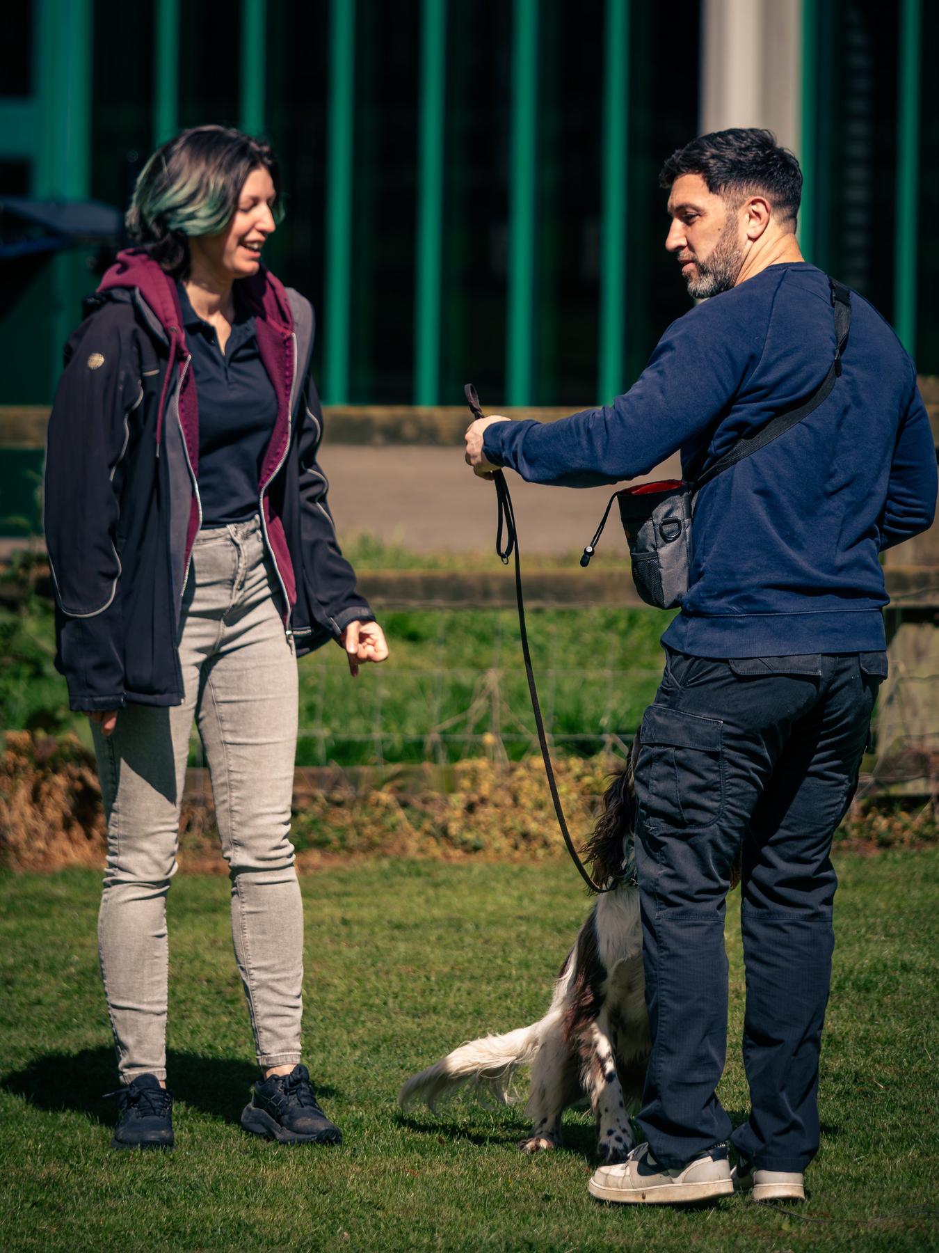 Ryan coaching an owner as her dog stays close on a lead