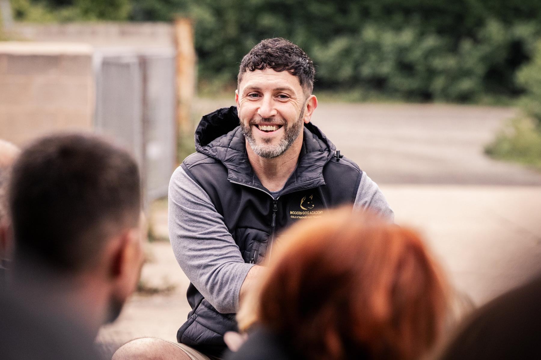 Ryan smiling as he talks to a group of dog owners at an outdoor session